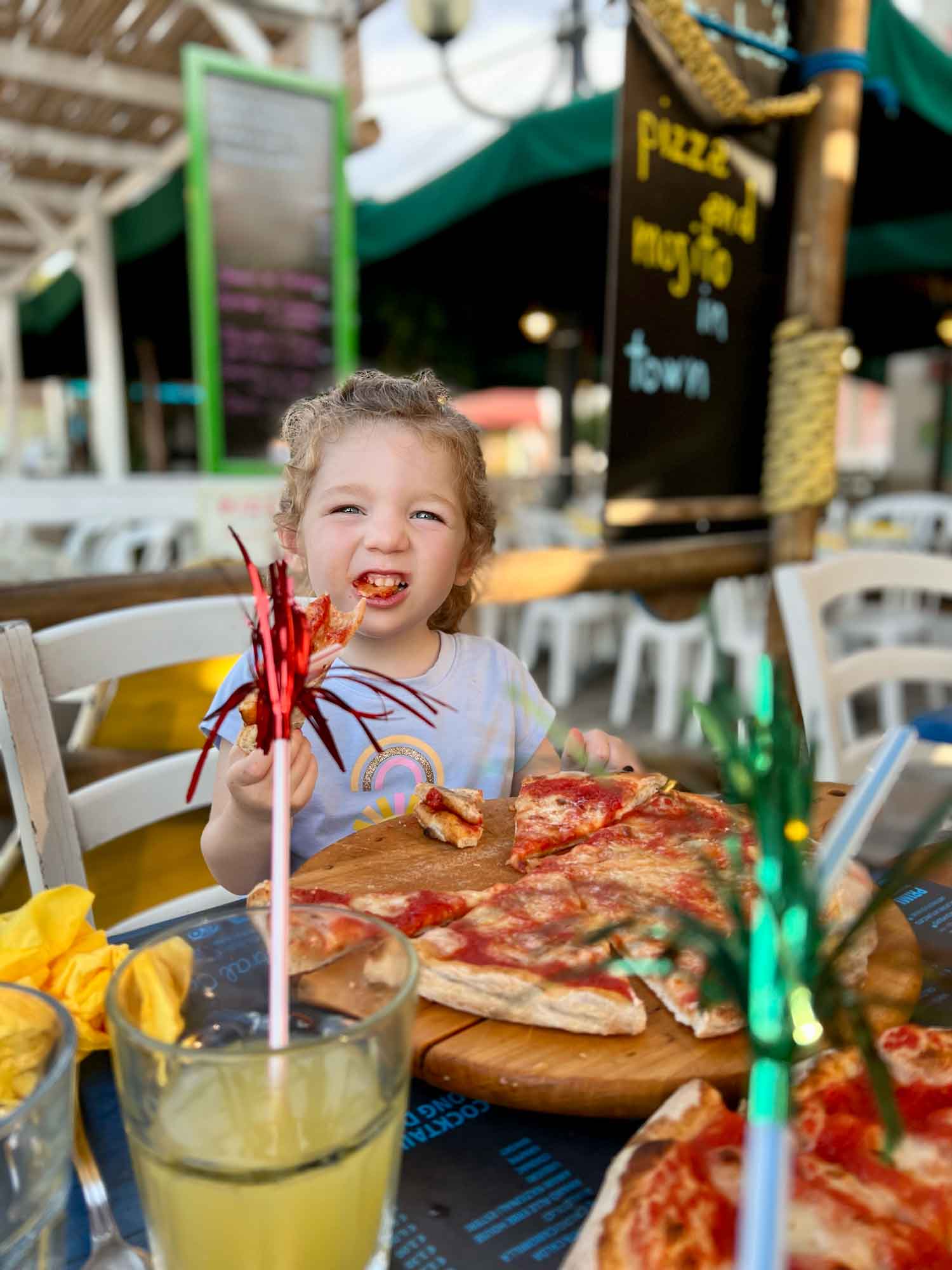 Kid smiling eating pizza