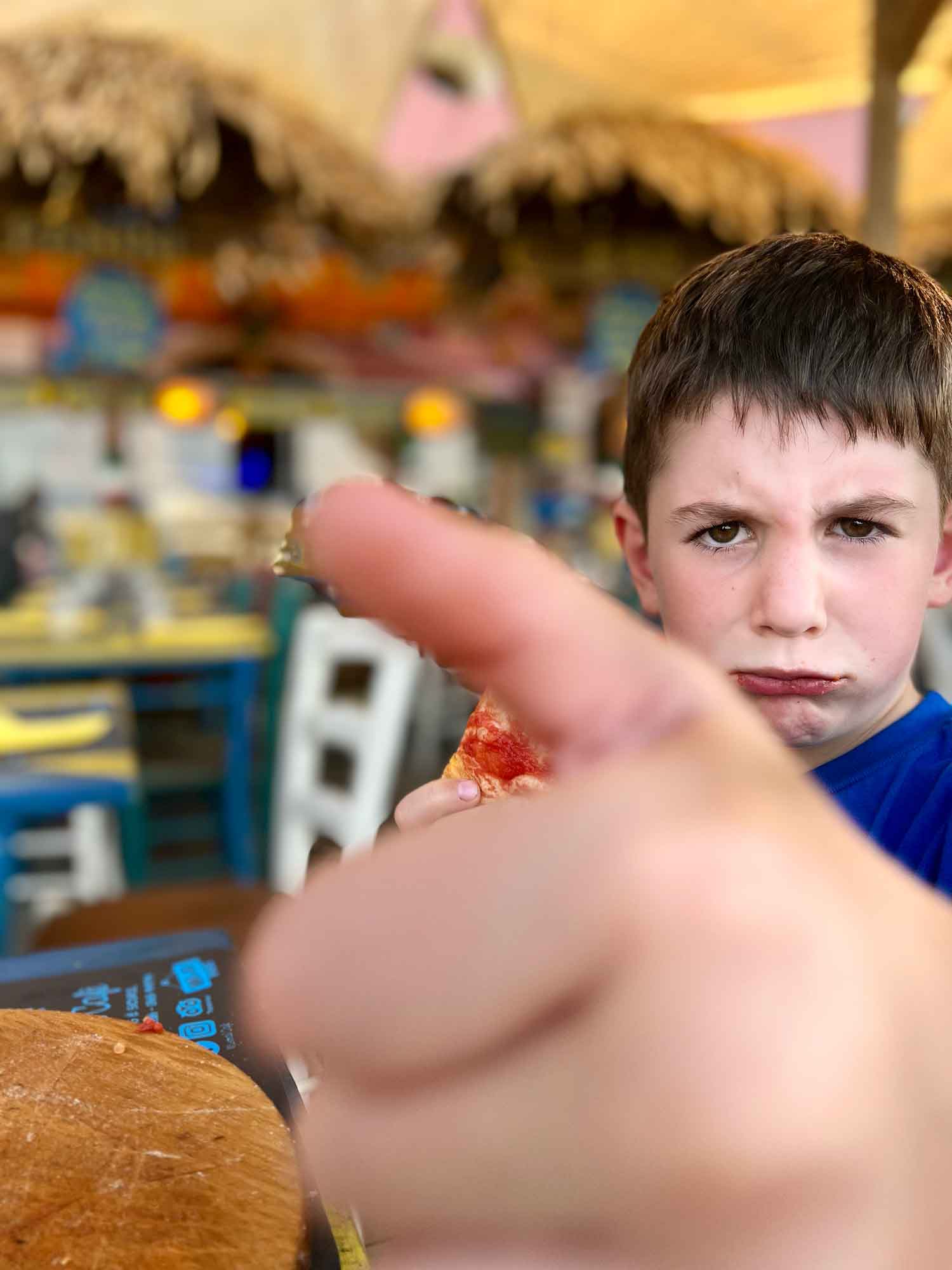 Kid trying to eat pizza with a frown