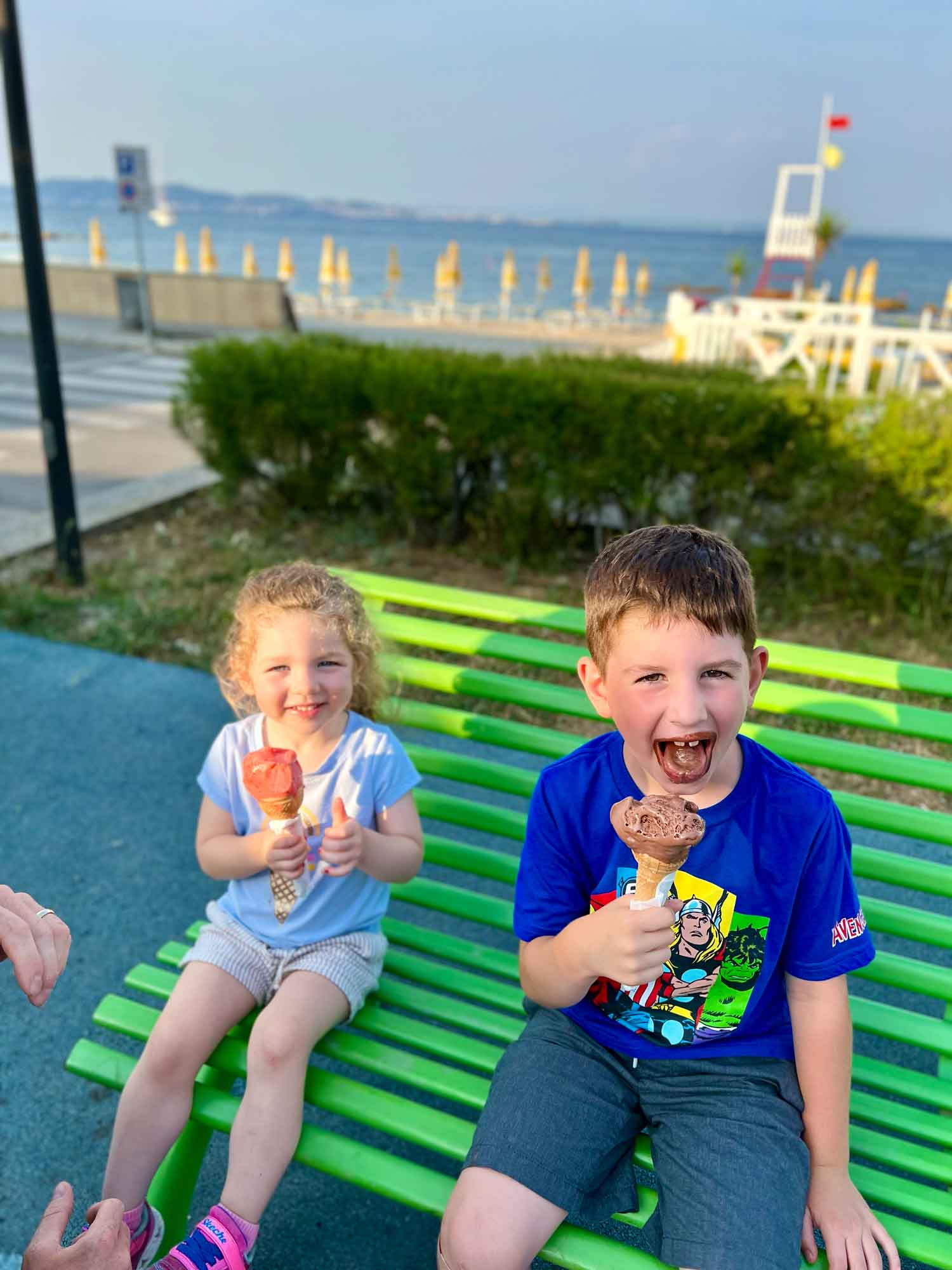two kids on a bench with ice cream ocnes