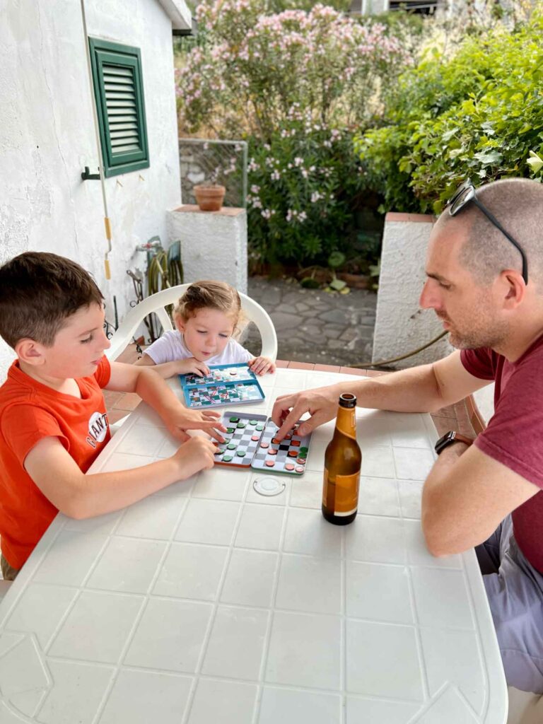 dad and two kids playing travel games on a outdoor table