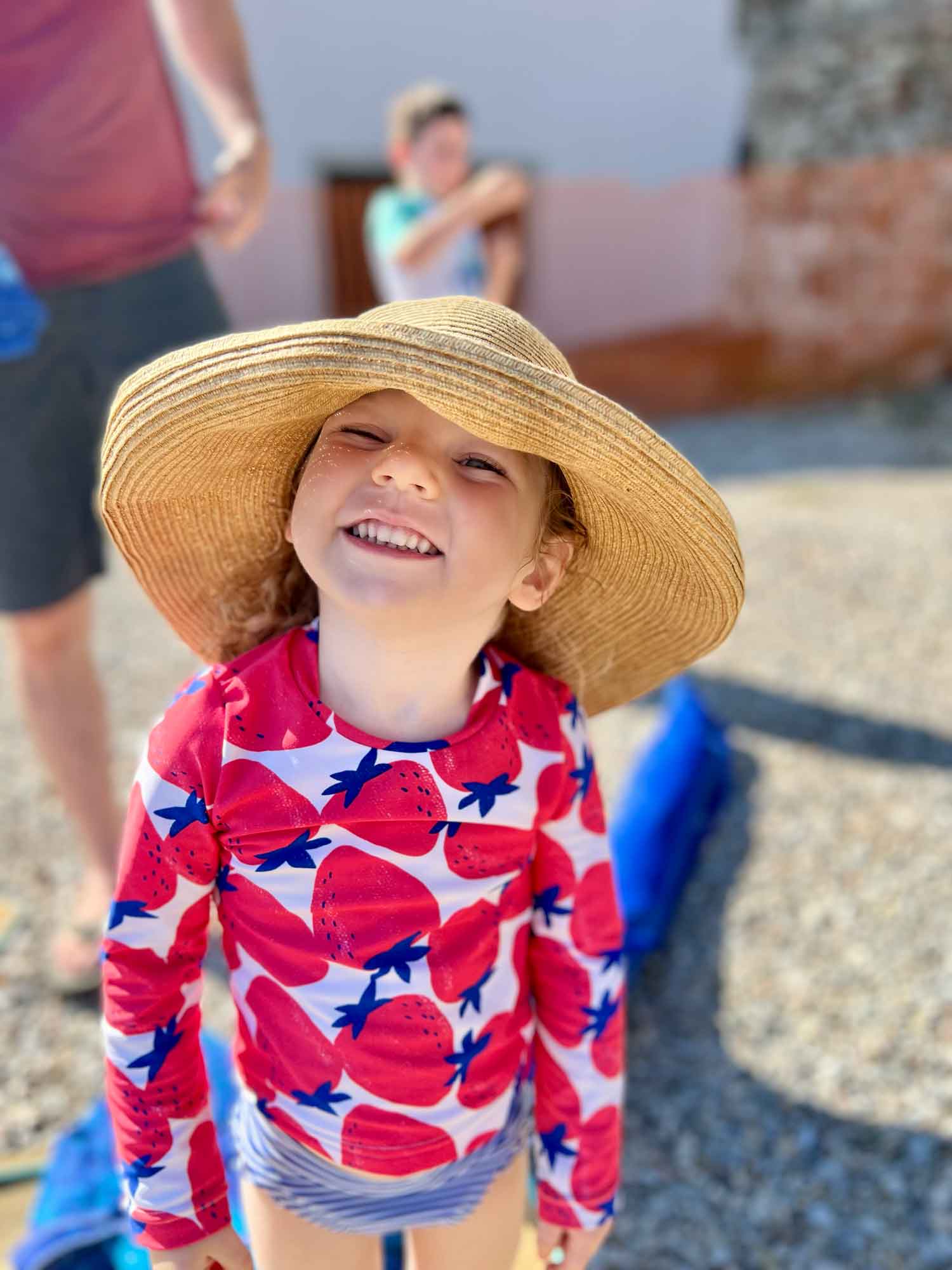 little girl at the beach with a straw hat