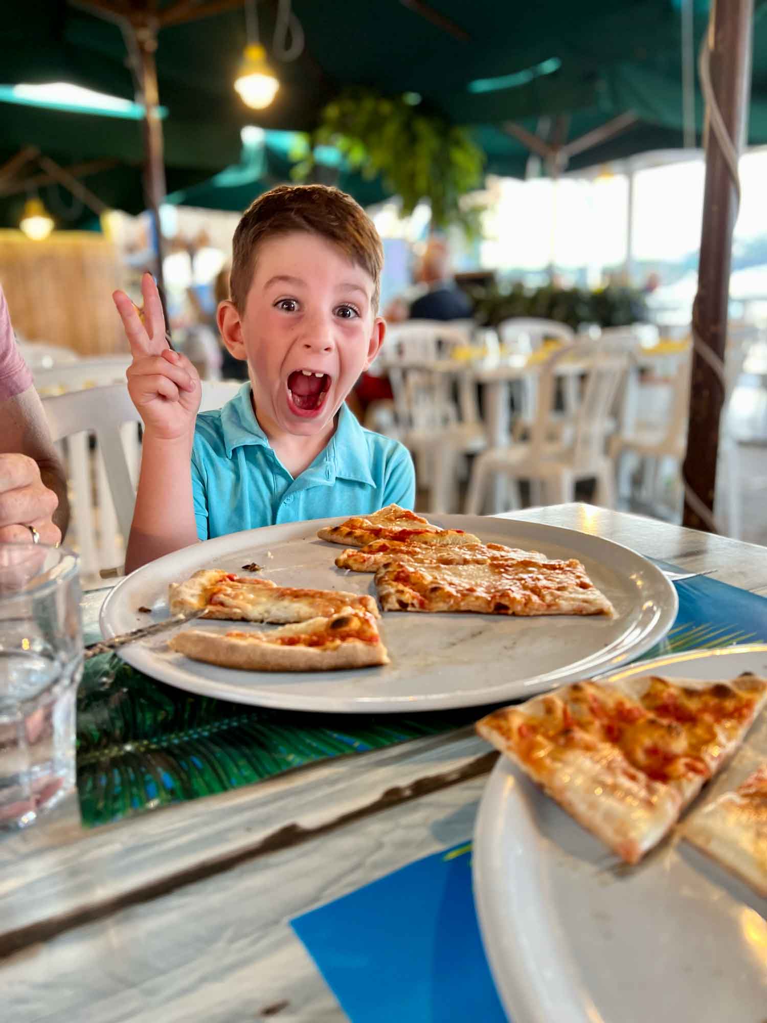 Little boy with excited face and a pizza in front of him