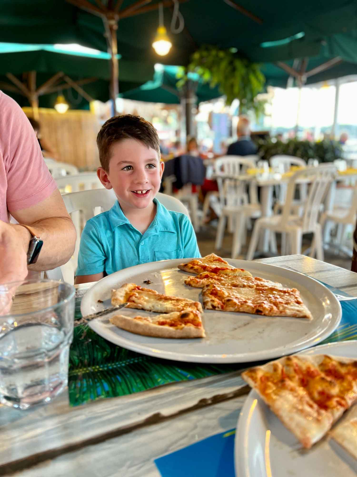 little boy at a restaurant with a pizza