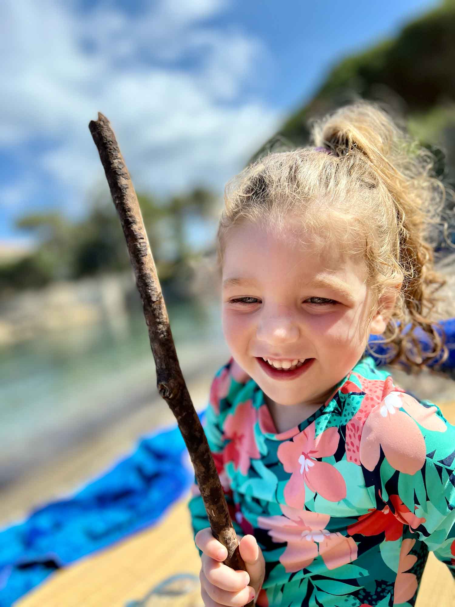 little girl with a stick at the beach