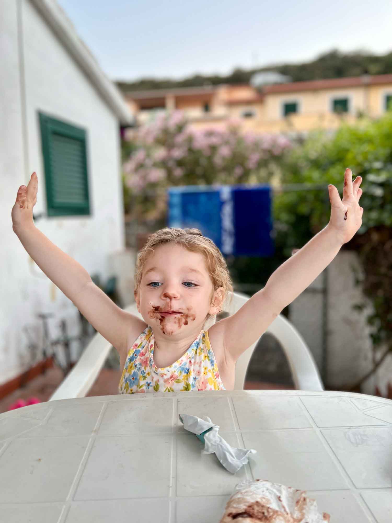 little girl with hands in the air and ice cream on her face