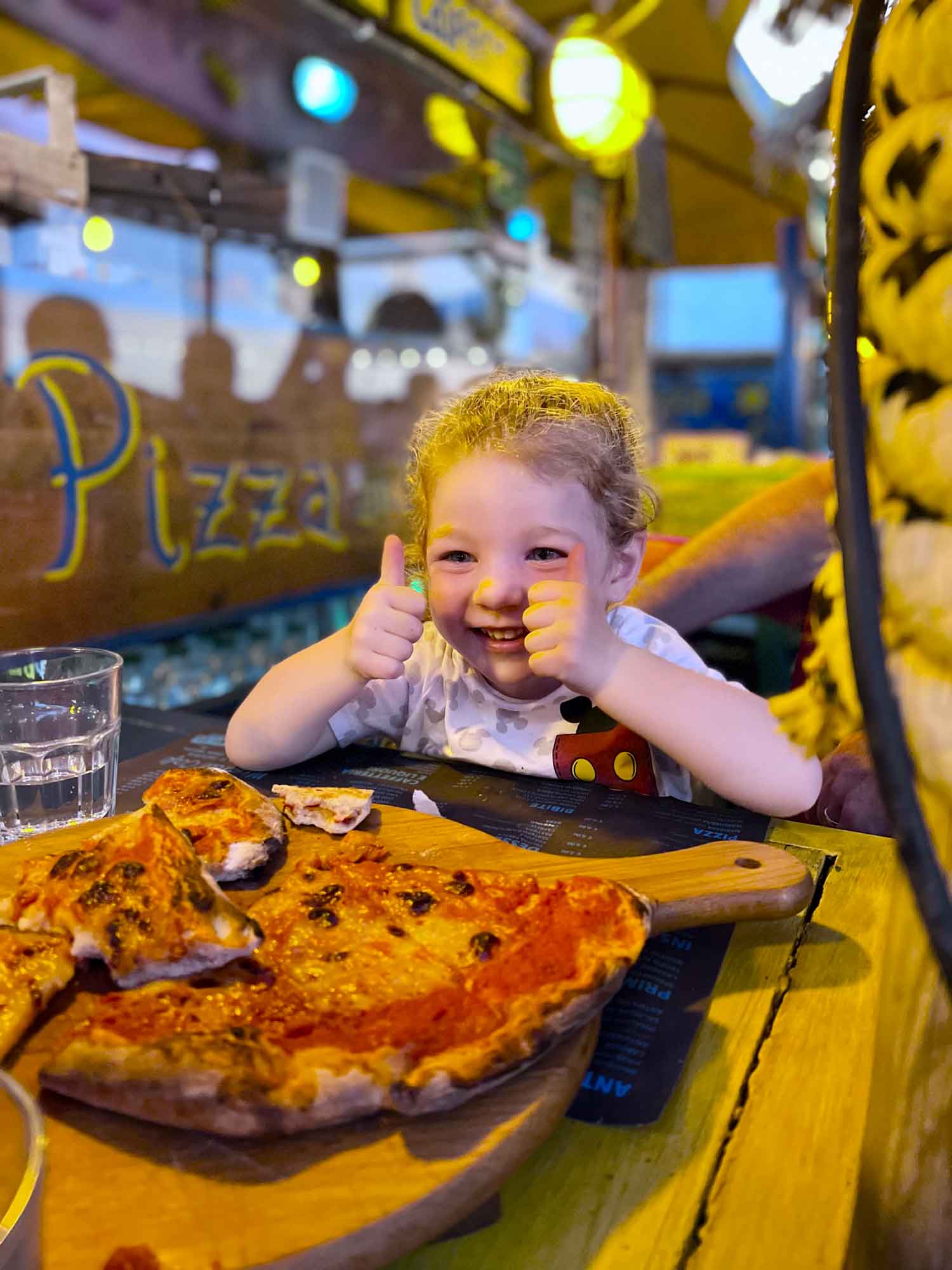 little girl with a pizza and a thumbs up