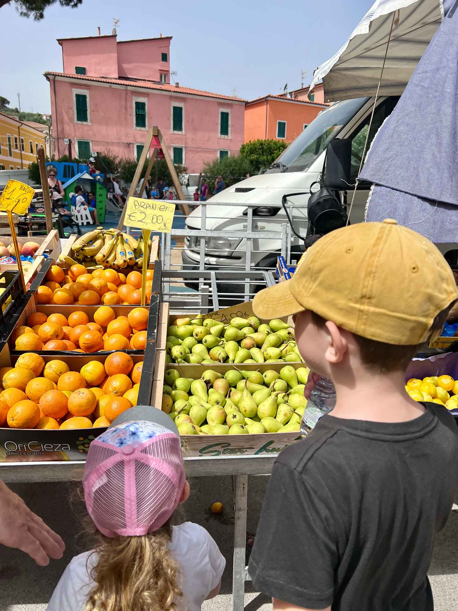two kids looking at produce at an outdoor market
