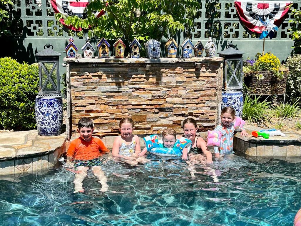 five kids sitting in a swimming pool