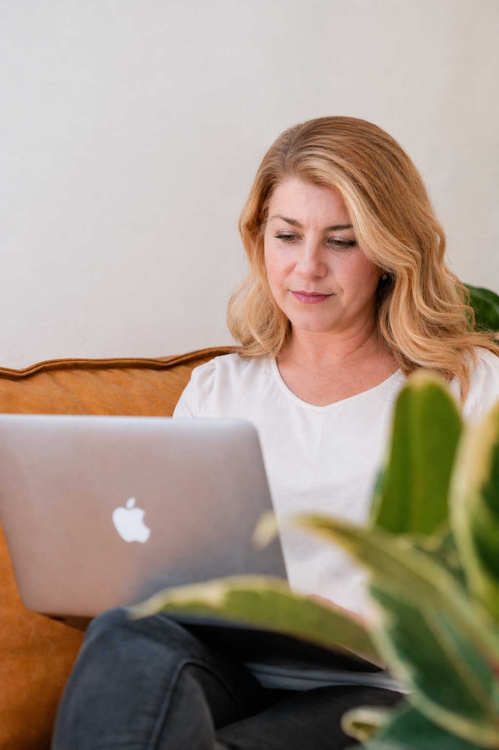 Colleen looking at her laptop while seated on a couch